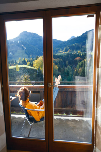 relax. girl sitting in a chair on a balcony with mountain view - Фото, изображение