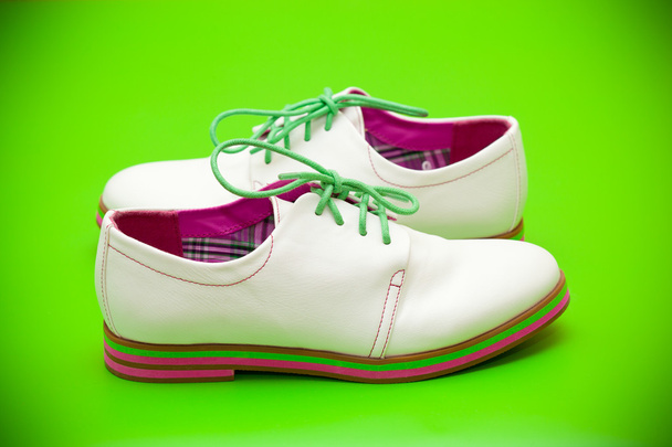 緑の背景に緑の靴ひもと白い靴 - Fotografie, Obrázek