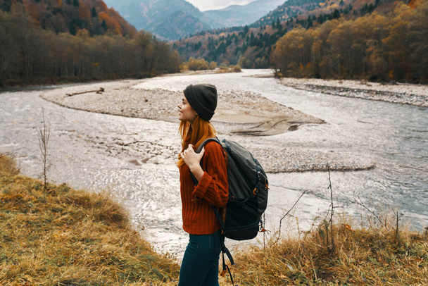 woman in autumn in the mountains with a backpack on her shoulders travel tourism river - Photo, Image
