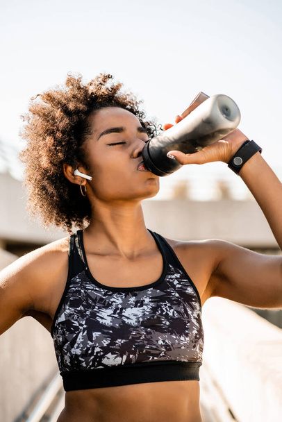 Афро атлет женщина питьевой воды после тренировки на открытом воздухе. - Фото, изображение