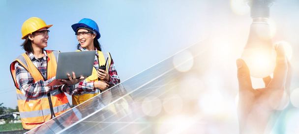 Female electrical engineers are holding a Laptop and working on the job site at the solar panel outdoors. Solar Power Management, Alternative Energy, Clean Energy concepts. - Photo, Image