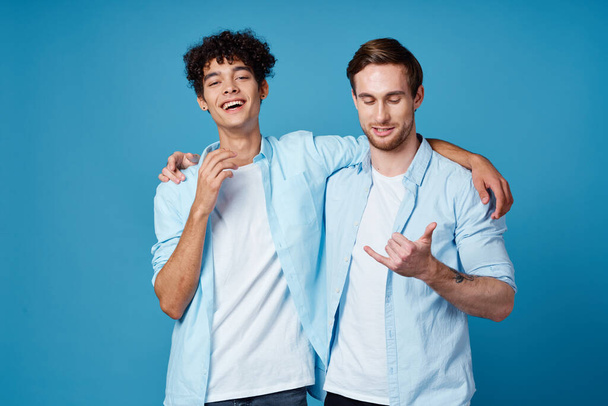 man with curly hair hugs his friend on blue background fun cropped view - Photo, Image