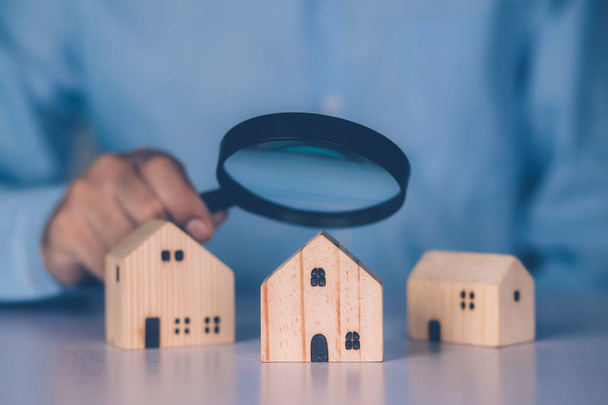 Ręka przedsiębiorcy posiadają szkło powiększające szuka domu do badania i analizy jakości, inspekcji i wyboru domu, zakupu i wyszukiwania mieszkaniowych i inwestycyjnych, koncepcji biznesu i nieruchomości. - Zdjęcie, obraz