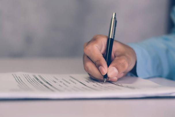 Les mains de l'homme d'affaires signant le contrat au sujet de l'accord pour le succès sur le bureau, la paperasserie de document de signature de l'homme avec stylo, l'assurance juridique et la décision pour l'affaire, concept d'entreprise. - Photo, image