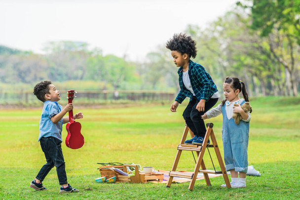multi gruppo etnico e diversificato di bambini si divertono a giocare insieme sul prato erboso nel parco - Foto, immagini