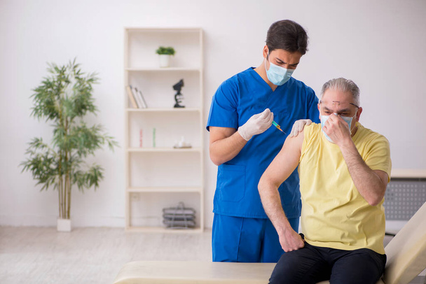 Öreg férfi beteg visting fiatal férfi orvos vakcinázási koncepció - Fotó, kép