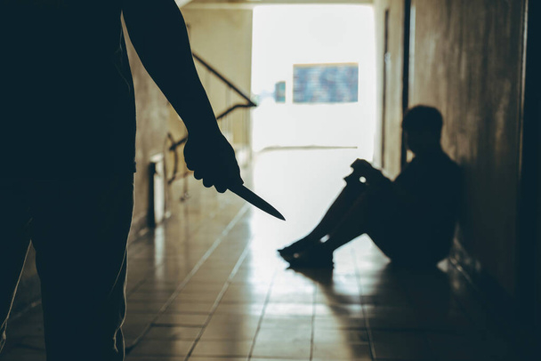 Violent man carries a knife attempting to attack a young man in front of the room.Domestic violence problems Concept. - Foto, Imagen
