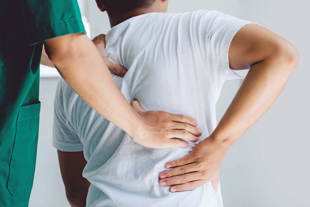 Male doctor therapist doing healing treatment on man's back.Back pain patient, treatment, medical doctor,massage for back pain relief office syndrome - Foto, Imagem