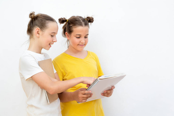 Zwei Mädchen mit Lehrbuch auf weißem Hintergrund. Teenager zeigt in einem Buch - Foto, Bild