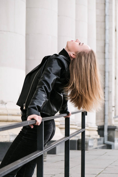 Portrait of young blonde woman with red lips wearing leather jacket on corporate building stairs. Career businesswoman. Urban street city lifestyle - Foto, Imagem