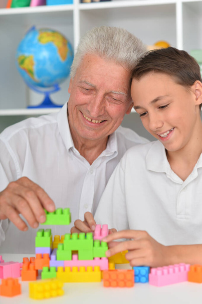 Smiling boy playing with colorful plastic blocks with grandfather  - Foto, Imagem