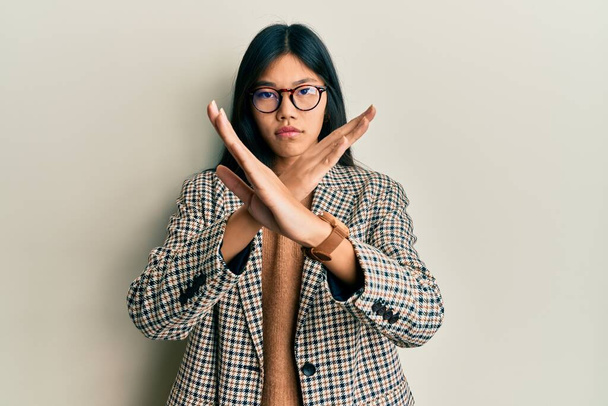 Young chinese woman wearing business style and glasses rejection expression crossing arms doing negative sign, angry face  - Foto, imagen