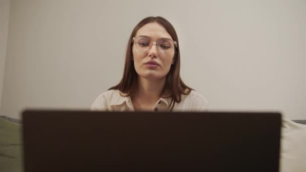 Una chica europea seria habla en un enlace de vídeo en un ordenador. - Metraje, vídeo