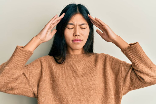 Nuori kiinalainen nainen päällään rento vaatteita käsi pään päällä, päänsärky, koska stressi. migreeni.  - Valokuva, kuva