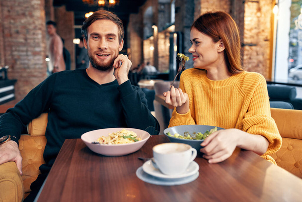 um homem e uma mulher estão sentados em uma mesa em uma refeição de restaurante deliciosa comida que serve pratos - Foto, Imagem