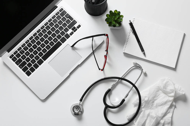 Composition with modern stethoscope and laptop on light background - Foto, imagen