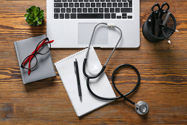 Composition with modern stethoscope and laptop on wooden background - Foto, imagen