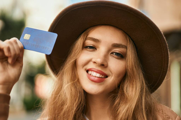 Young blonde girl smiling happy holding credit card at the city. - Фото, зображення