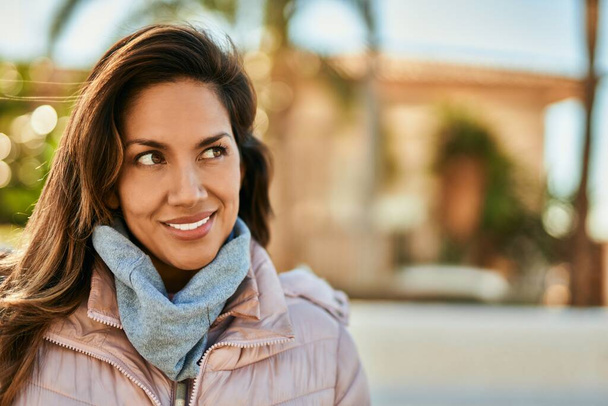 Молода іспаномовна жінка посміхається щаслива стоячи в місті
. - Фото, зображення