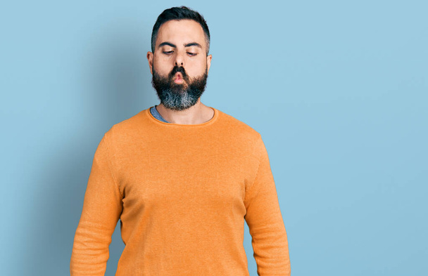 Hispanic man with beard wearing casual winter sweater making fish face with lips, crazy and comical gesture. funny expression.  - Foto, immagini
