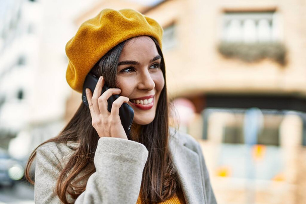 Молода іспаномовна дівчина посміхається щаслива розмова на смартфоні в місті
. - Фото, зображення