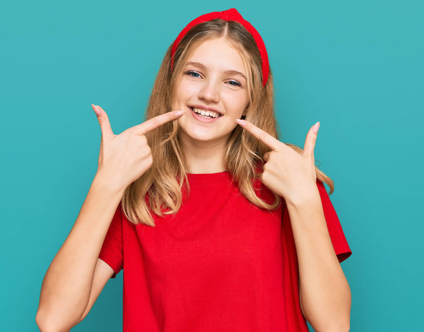 Gyönyörű fiatal kaukázusi lány, alkalmi piros pólóban, vidám mosollyal, ujjakkal és szájjal mutogatva. fogászati egészség fogalma.  - Fotó, kép