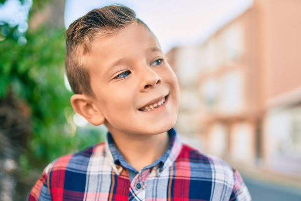 Чарівний білий хлопчик посміхається щасливий стоячи в місті
. - Фото, зображення
