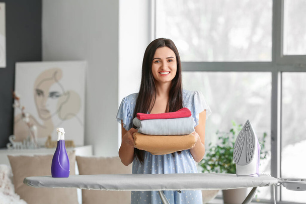 Young woman with ironed clothes at home - Foto, imagen