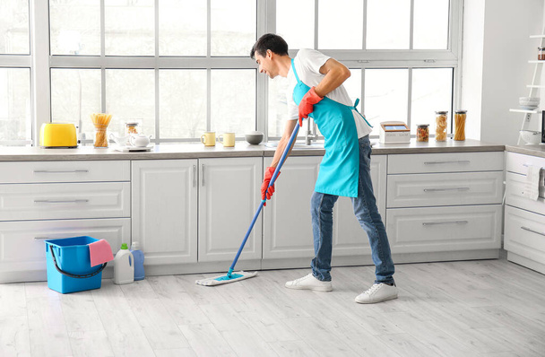 Jovem esfregando chão na cozinha - Foto, Imagem
