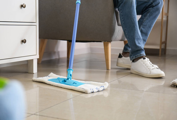 Young man with floor mop in living room, closeup - Photo, Image