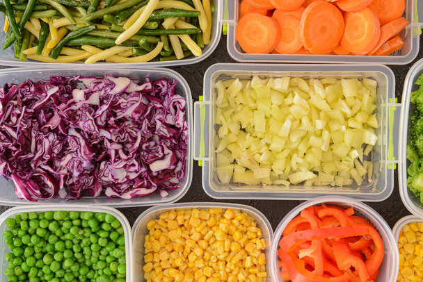 Envases de plástico con diferentes verduras como fondo, primer plano - Foto, Imagen