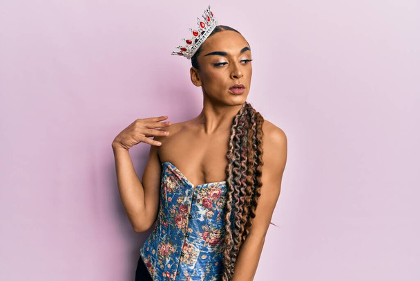 Sensual mujer transgénero hispana usando corona de reina y posando glamorosa con cara seductora usando lencería sexy - Foto, Imagen