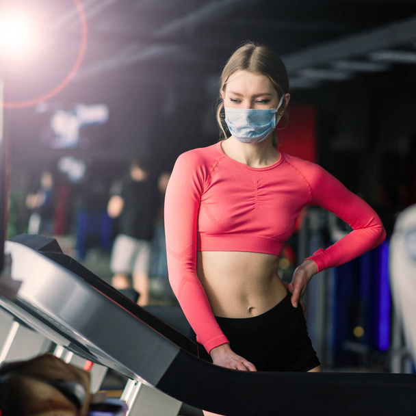 Femme portant un masque facial séance d'entraînement dans la salle de gym pendant le virus corona pandermique, covide - Photo, image