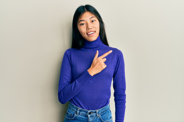 Young chinese woman wearing casual clothes smiling cheerful pointing with hand and finger up to the side  - Photo, Image