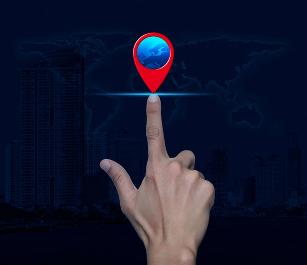 Hand pressing map pin point location button over world map, modern city tower and skyscraper, Map pointer navigation concept, Elements of this image furnished by NASA - 写真・画像
