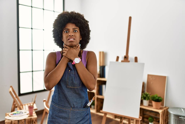 Młoda Afroamerykanka z afro-włosami w studiu artystycznym krzyczy: "Duś się, bo boli cię gardło". problemy zdrowotne. koncepcja uduszenia i samobójstwa.  - Zdjęcie, obraz