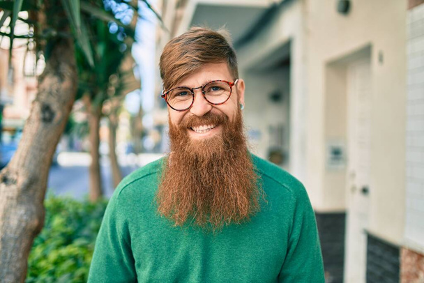 Joven irlandés con barba pelirroja sonriendo feliz caminando por la ciudad. - Foto, Imagen