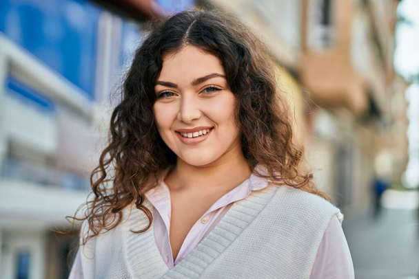 Μια νεαρή Ισπανίδα χαμογελαστή ευτυχισμένη στέκεται στην πόλη.. - Φωτογραφία, εικόνα