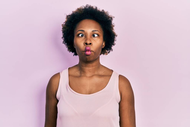 Young african american woman wearing casual sleeveless t shirt making fish face with lips, crazy and comical gesture. funny expression.  - Photo, Image