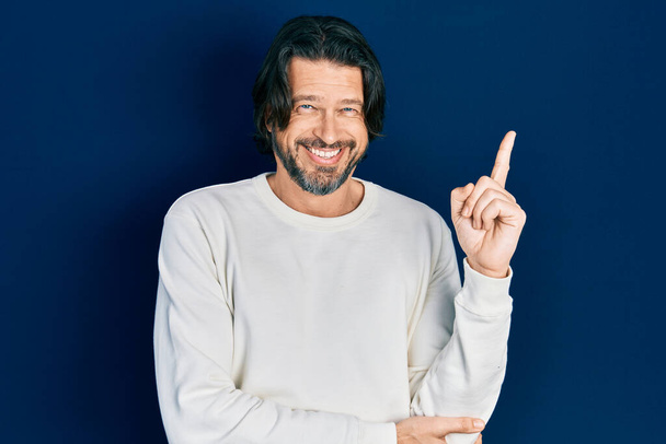Middle age caucasian man wearing casual clothes with a big smile on face, pointing with hand and finger to the side looking at the camera.  - Photo, Image