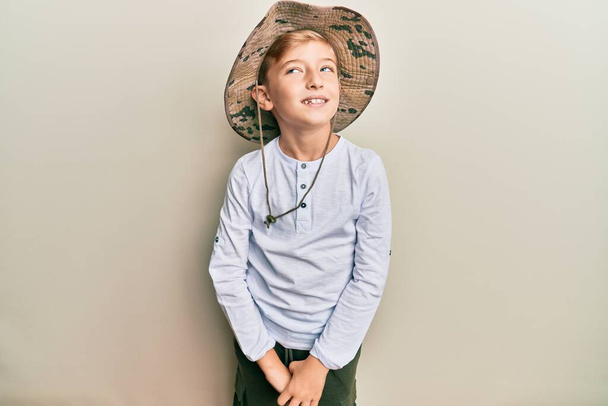 Malý kavkazský chlapec kluk nosí průzkumný klobouk dívá na stranu, relaxační profil póza s přirozenou tváří a sebevědomý úsměv.  - Fotografie, Obrázek
