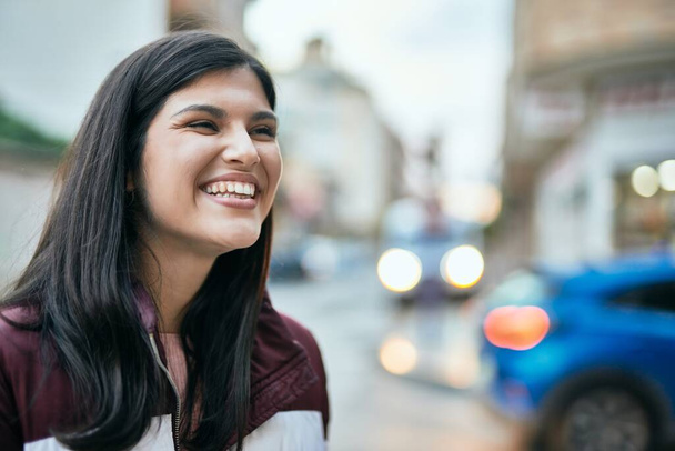 Giovane ragazza ispanica sorridente felice in piedi alla città. - Foto, immagini