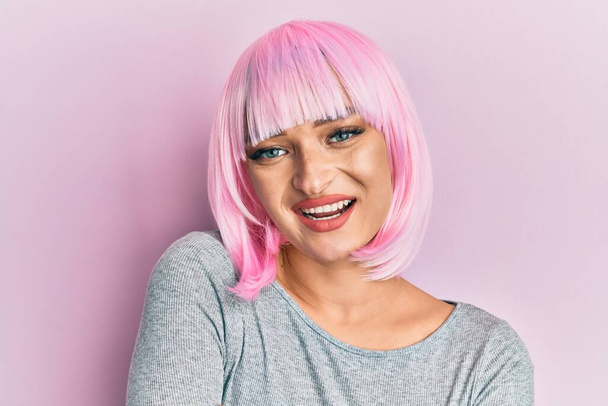 Young caucasian woman wearing pink wig happy face smiling with crossed arms looking at the camera. positive person.  - Photo, Image