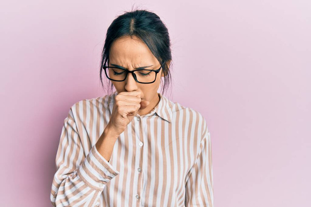 Chica hispana joven que usa ropa casual y gafas sintiéndose mal y tosiendo como síntoma de resfriado o bronquitis. concepto de atención sanitaria.  - Foto, Imagen