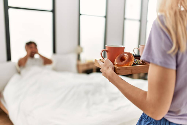 Γυναίκα έκπληξη φίλο της με πρωινό στο κρεβάτι στο σπίτι. - Φωτογραφία, εικόνα