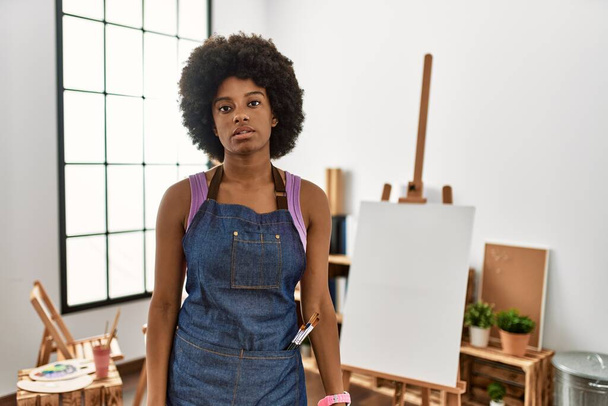 Młoda Afroamerykanka z afro włosy w studio sztuki zrelaksowany z poważnym wyrazem twarzy. proste i naturalne patrzenie w kamerę.  - Zdjęcie, obraz