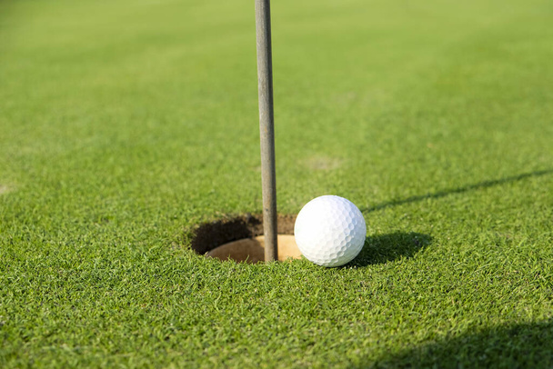 мяч на поле для гольфа рядом с лункой. Высокое качество фото - Фото, изображение