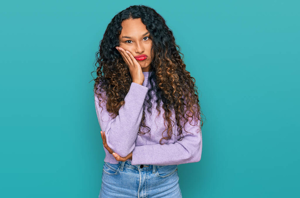 Young hispanic woman with curly hair wearing casual winter sweater thinking looking tired and bored with depression problems with crossed arms.  - Photo, image