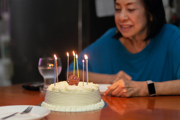 Hijas mano encendiendo velas en senior con otro pastel de cumpleaños. - Foto, imagen