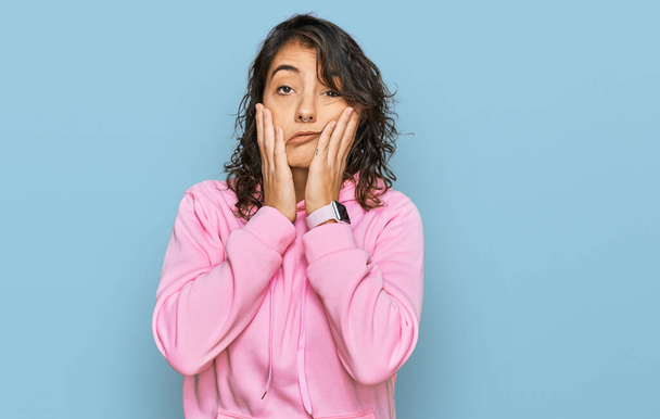 Junge hispanische Frau trägt lässiges Sweatshirt müde Hände, die Gesicht, Depression und Traurigkeit verdecken, verärgert und irritiert wegen des Problems  - Foto, Bild